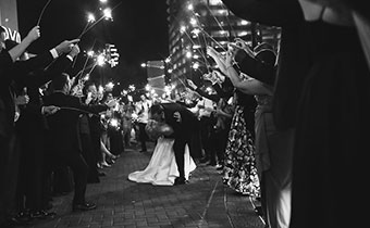 bride and groom kissing with guests holding sparklers
